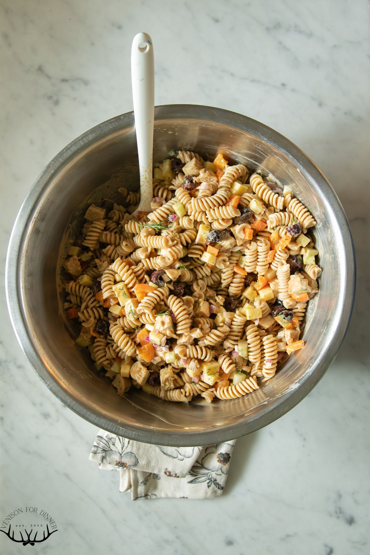 Spoon in a bowl of chicken pasta salad.