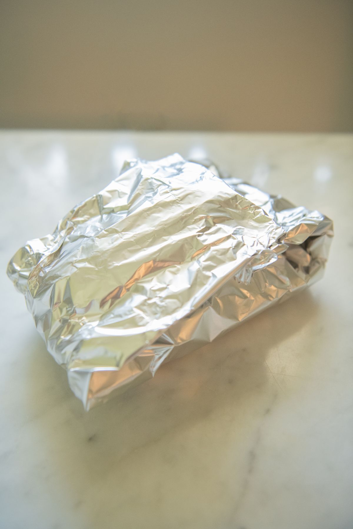 Pork chop and veggies wrapped in a foil packet.