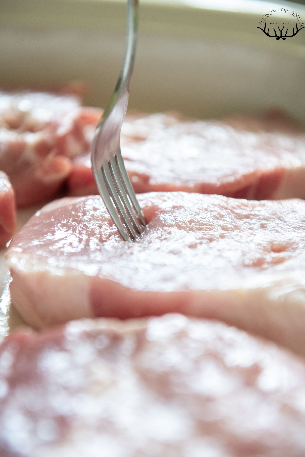 Fork poking holes in pork chops.