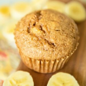 A banana spelt muffin surrounded by banana slices.