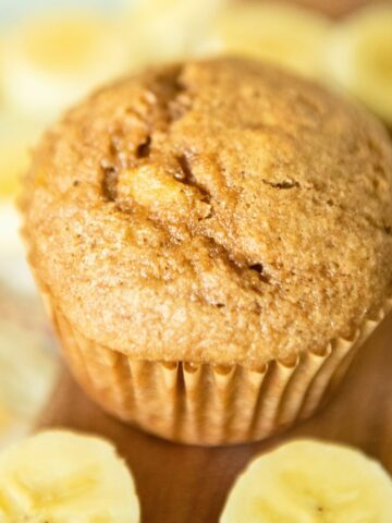 A banana spelt muffin surrounded by banana slices.