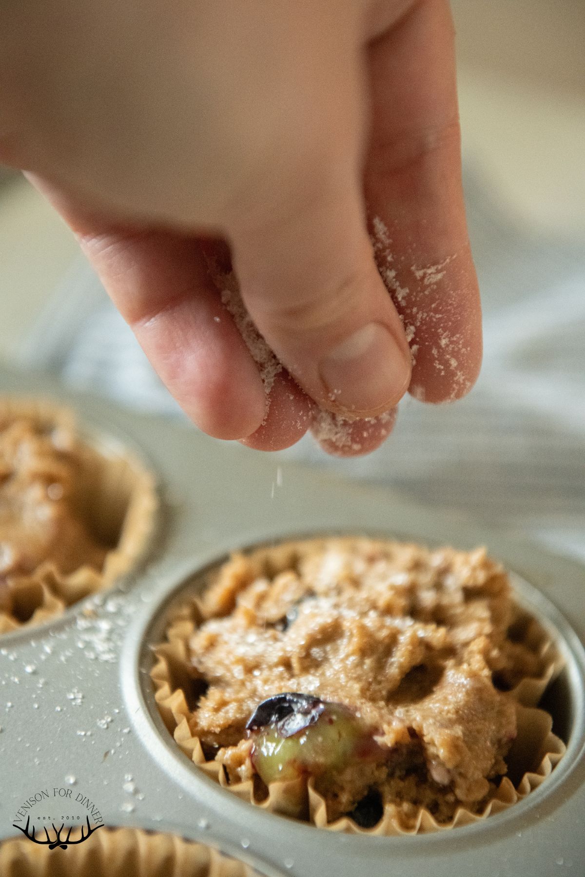 Sprinkling sugar over muffin batter.