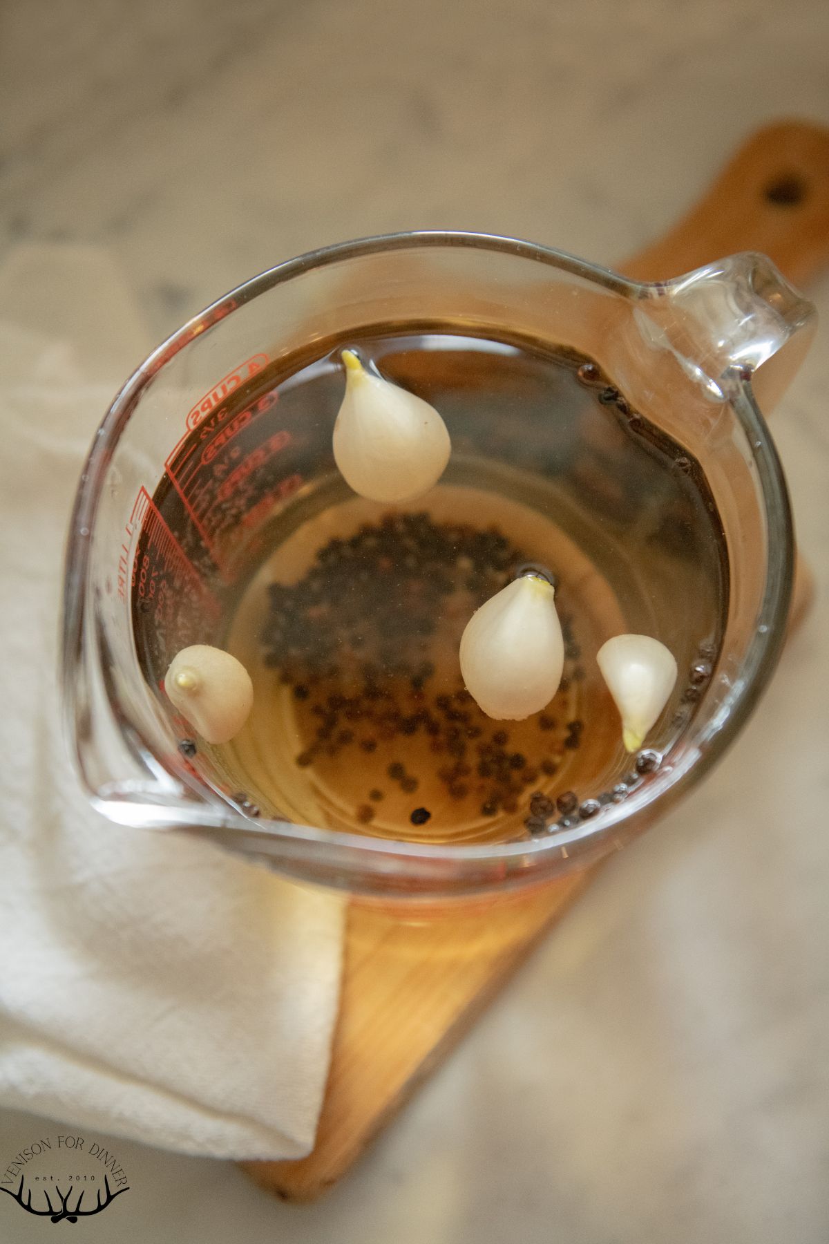 Garlic cloves in a measuring cup of brine.