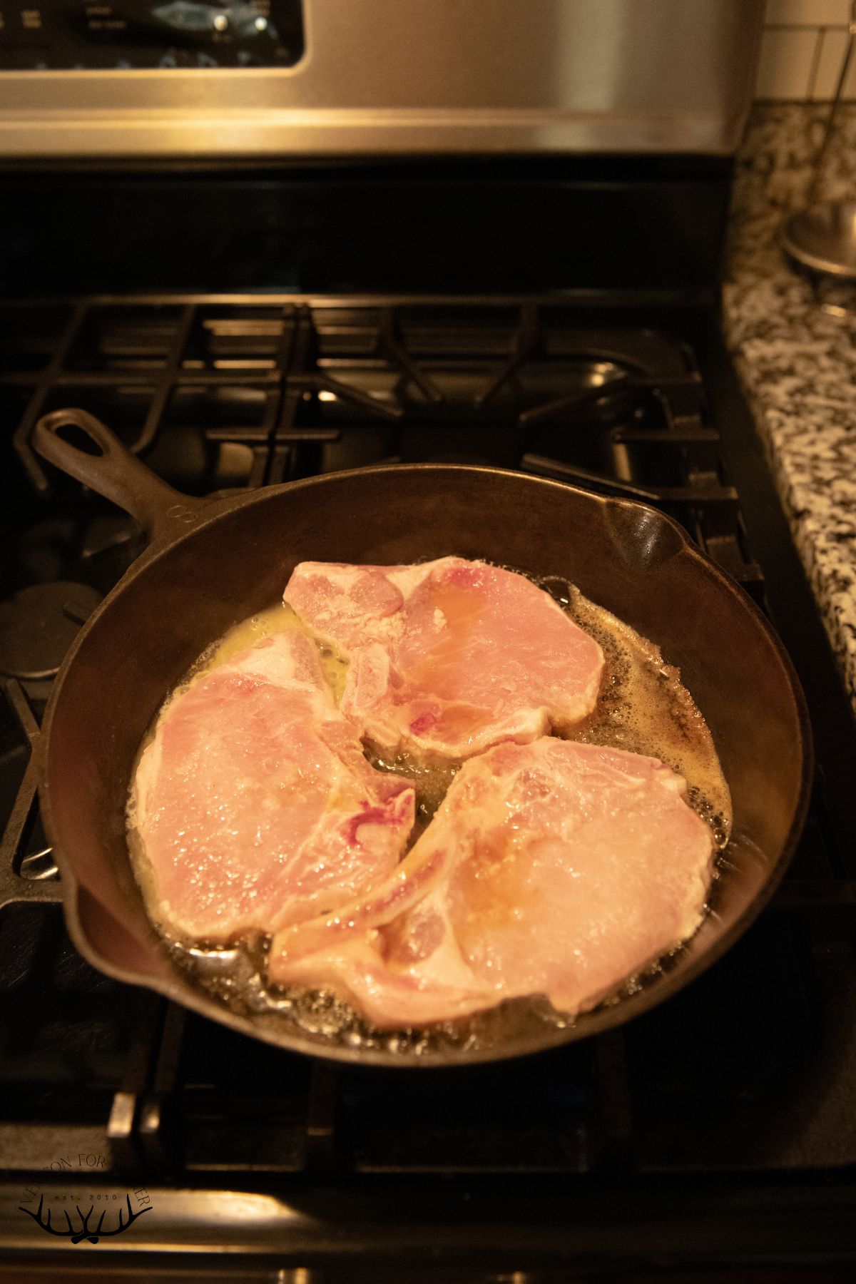 Bone-in pork chops in a skillet of butter.