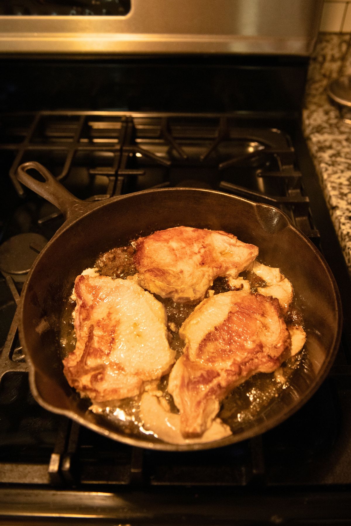 Searing pork chops in a cast iron skillet.