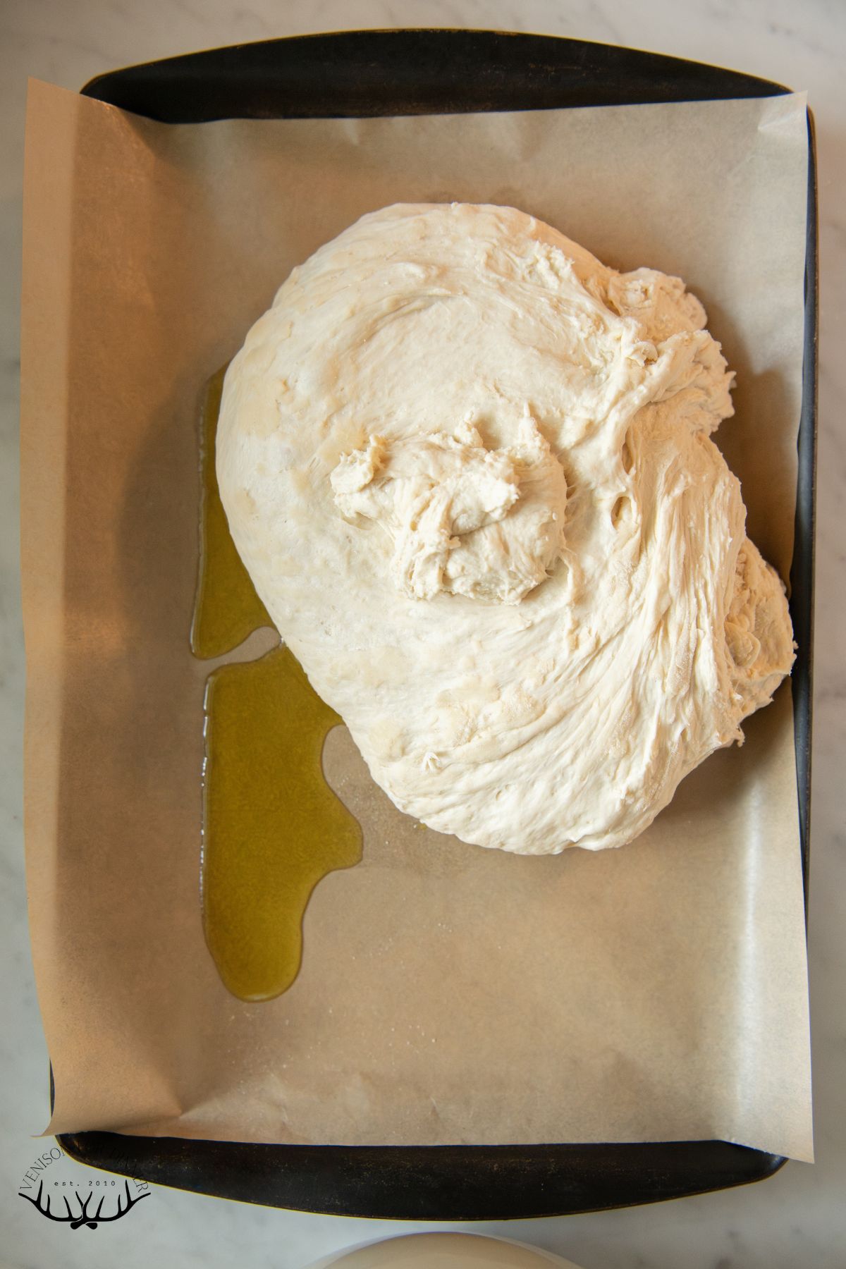 Focaccia dough resting on parchment paper.