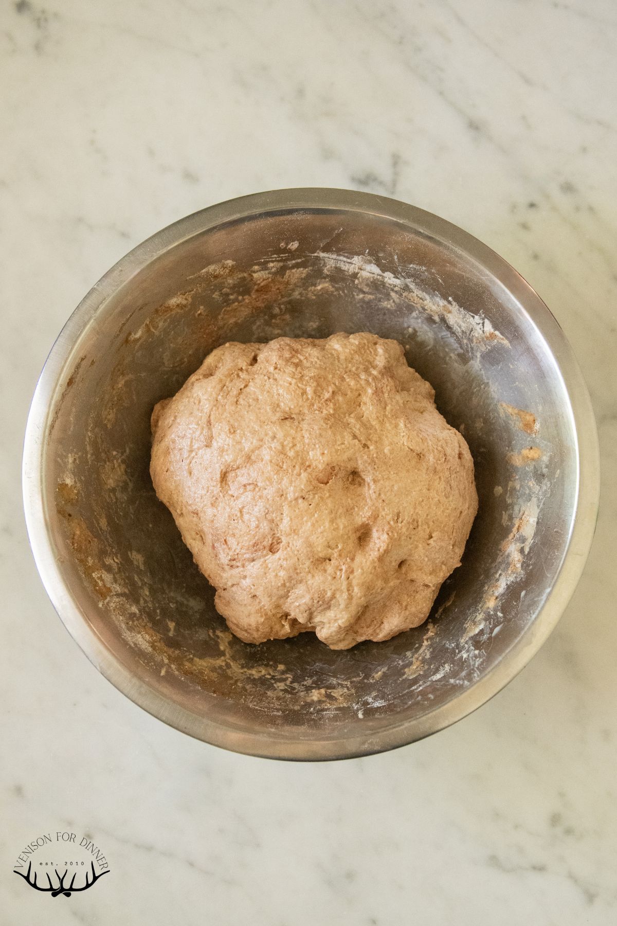 Sourdough brown bread dough in a mixing bowl.