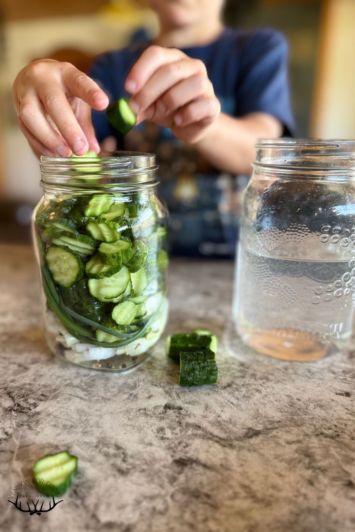 Adding sliced cucumbers to a jar.