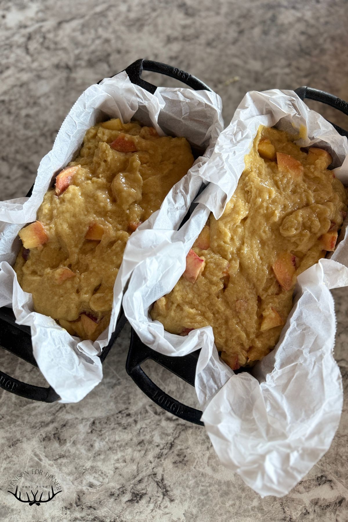 Peach batter in lined loaf pans.