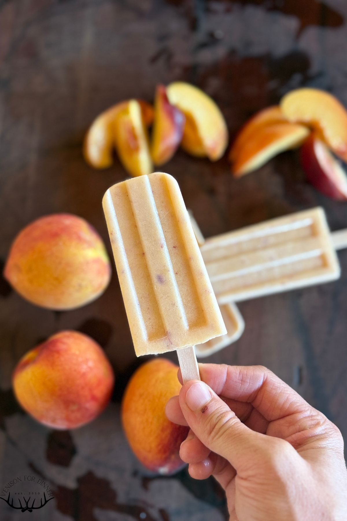 Hand holding a fresh peach popsicle.