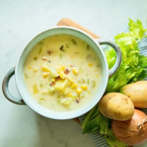 A bowl of corn and potato chowder with bacon.