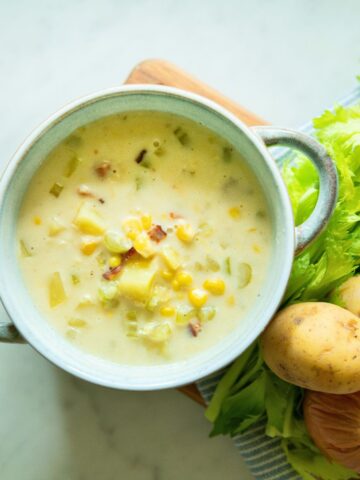 A bowl of corn and potato chowder with bacon.