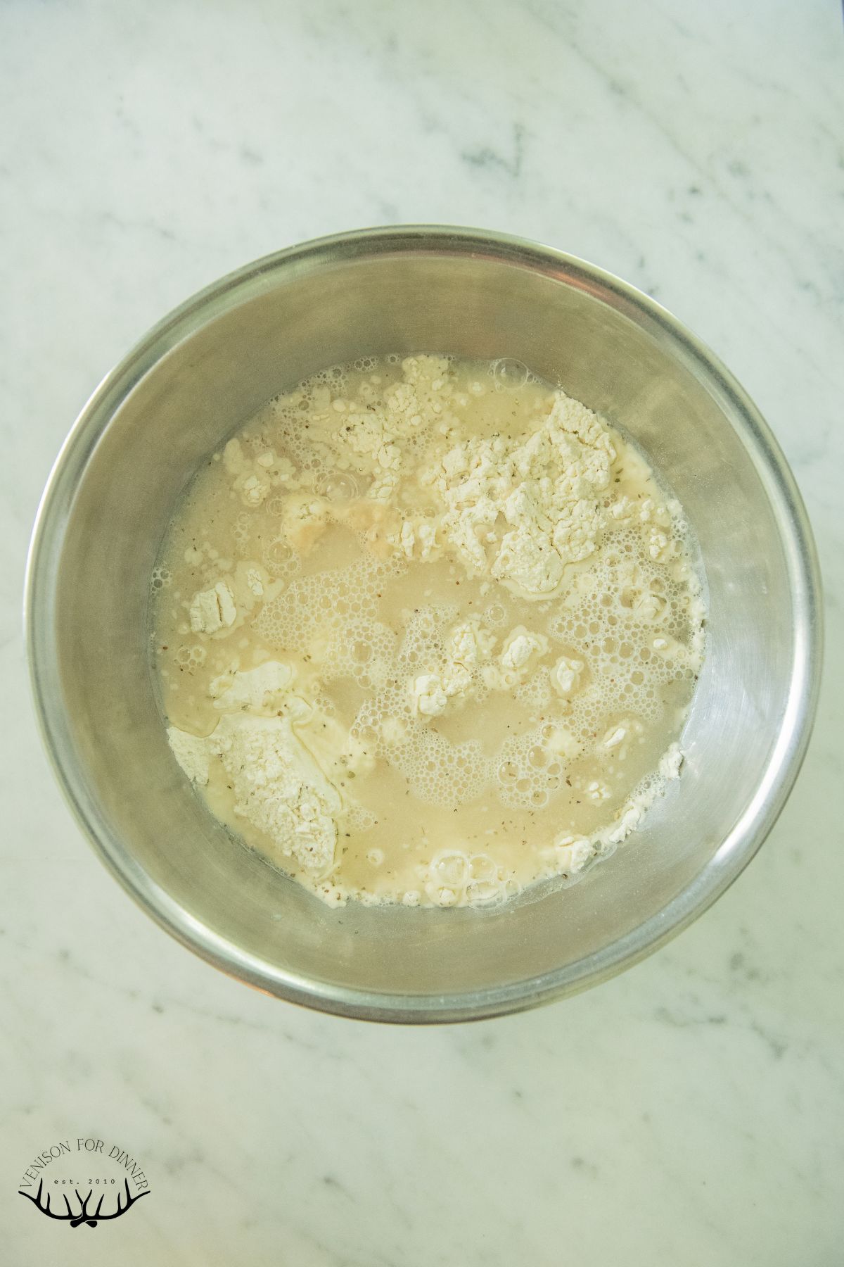 Wet ingredients added to a bowl of flour.