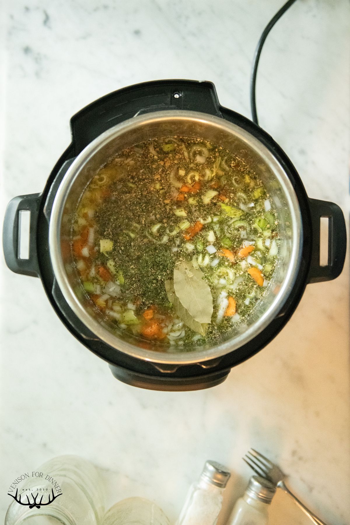 Seasoning and bay leaf in an instant pot of soup.