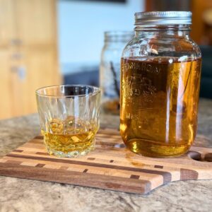 Jar of homemade spiced rum with a sample.