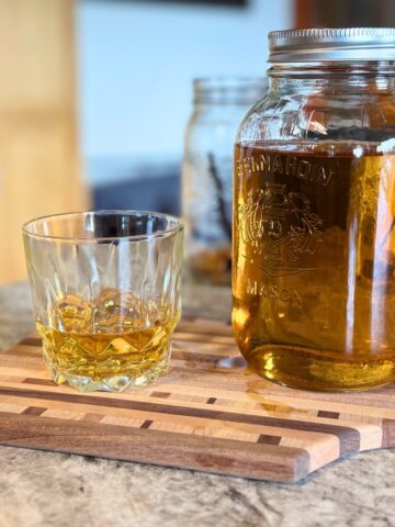 Jar of homemade spiced rum with a sample.