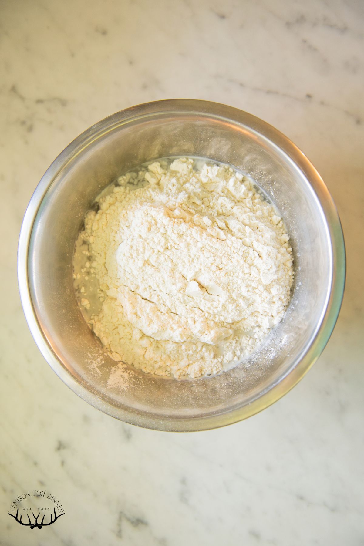 Flour added to a bowl of sourdough starter.