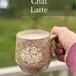 Hand holding a mug of pumpkin spice chai.